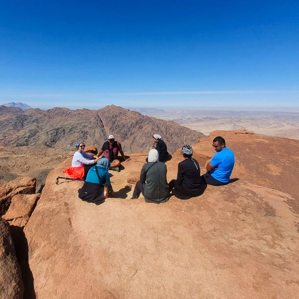 A group of Egyptian hikers taking a break on Mount Na'ga during a Sinai trekking journey