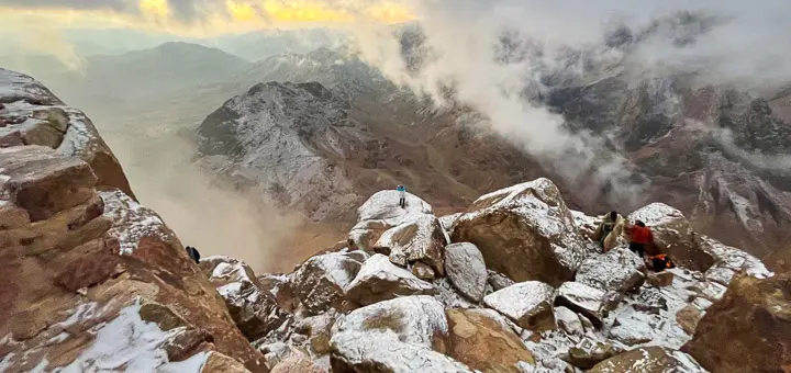 A serene morning view from Mount Sinai after a snowy night, with white-covered peaks, frost-tipped rocks, and soft light spreading across the silent, sacred landscape.