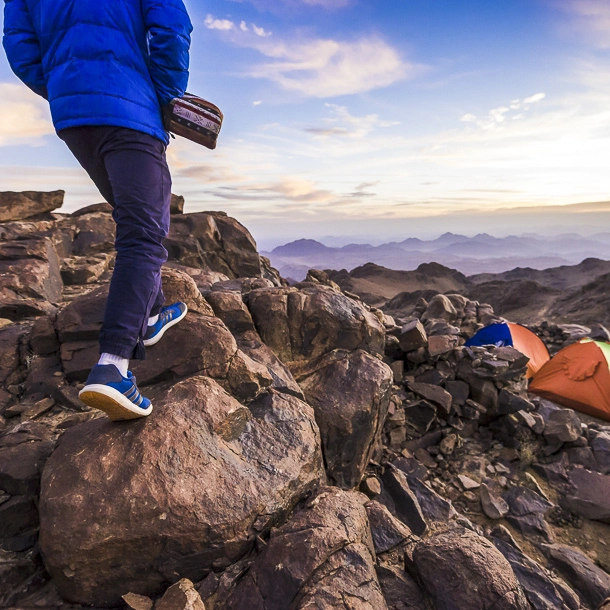 Trekker walking down Mount Catherine at sunrise after a cold overnight stay, returning to camp in the early morning light.