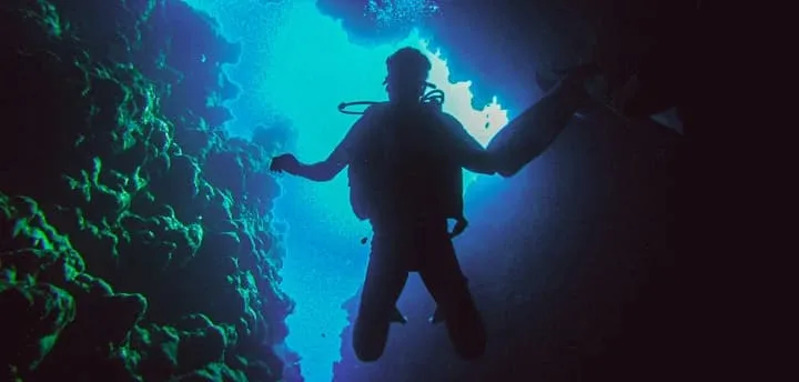Top 10 things to do in Sinai in 2025 A scuba diver glides through the clear blue waters of Dahab, surrounded by colorful coral reefs and marine life, capturing the beauty of South Sinai’s famous diving spots.
