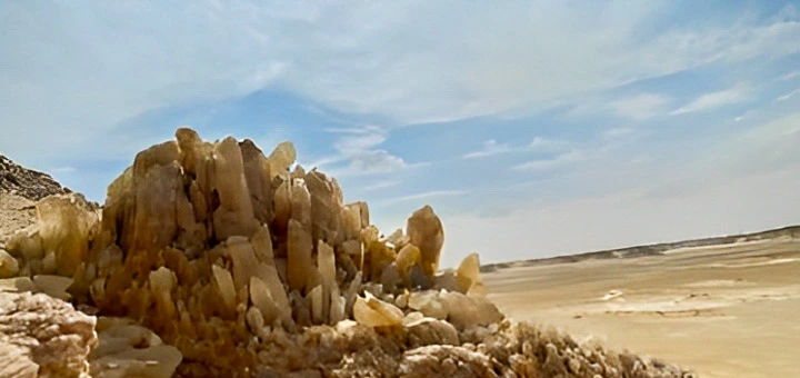 Quartz-rich arch and crystal-studded rock surfaces of Crystal Mountain in Egypt’s White Desert under a clear blue sky