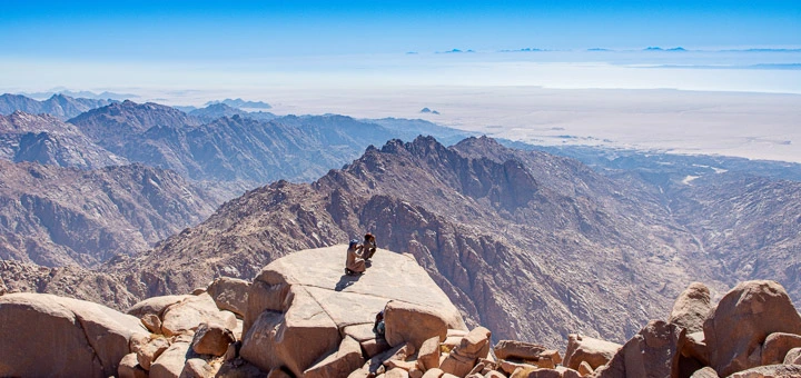 Two Bedouins resting on Mount Umm Shomar with the Red Sea and Egypt Mountains coastline in the background.
