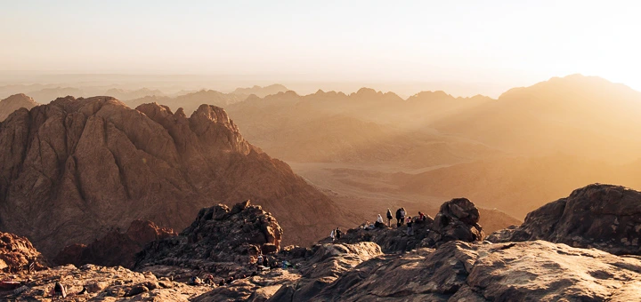 Morning view from the summit of Mount Sinai with golden sunlight over the surrounding Egypt Mountains and valleys.