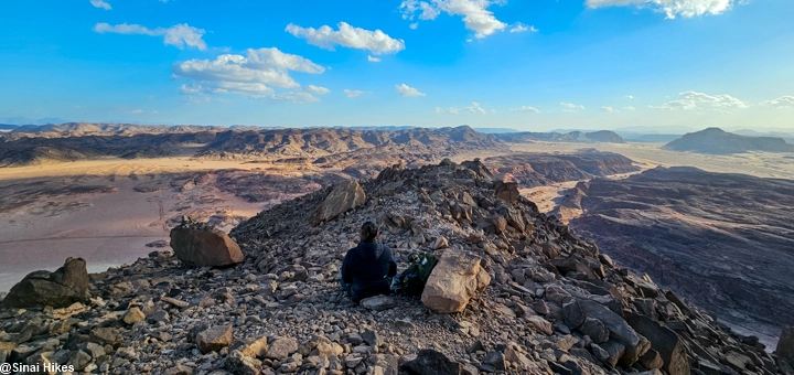 Lone hiker enjoying panoramic desert views from the trail of Mount Mileihis in the Sinai Mountains.