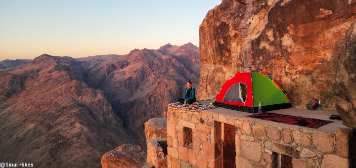 A woman sitting beside her tent at sunrise near the summit of Mount Sinai, 2,285 meters above sea level.