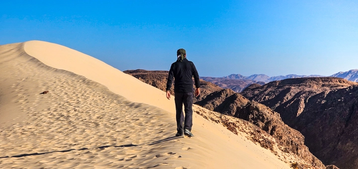 Hiker walking along a sand dune in the Sinai Desert